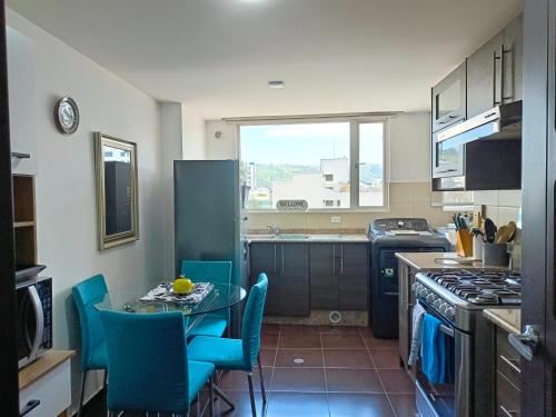 a kitchen with a table and blue chairs in it at CENTRAL Apartment, 3Beds - Balcony - Parking - 6thFLOOR in Quito