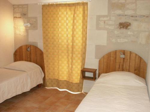 a bedroom with two beds and a yellow curtain at Gîte authentique au cœur de la forêt près de Chinon - FR-1-381-232 in Saint-Benoît-la-Forêt