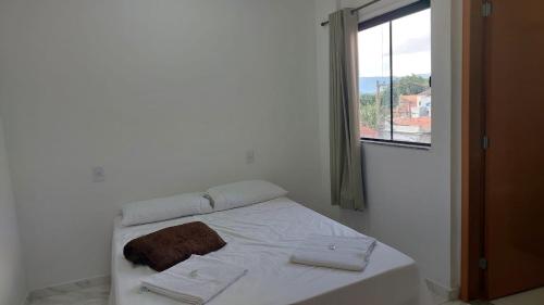 a bed in a white room with a window at Hotel Milagre Das Águas in Aparecida