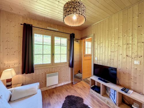 un salon avec un canapé et une télévision à écran plat dans l'établissement Demi-chalet à deux pas des remontées mécaniques avec Wifi - FR-1-560-6, à Combloux