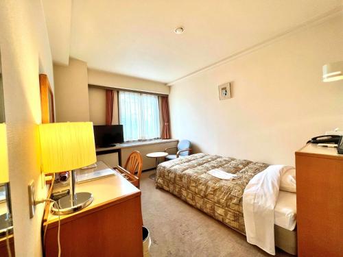 a hotel room with a bed and a desk at Hotel Tetora Makuhari Inagekaigan (Formerly Business Hotel Marine) in Chiba