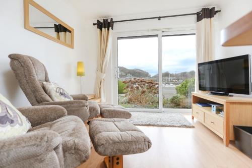 a living room with two chairs and a flat screen tv at 66D South Snowdon Wharf in Porthmadog