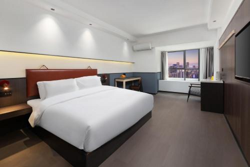a bedroom with a large white bed and a window at Mcsrh Hotel-Chengdu Jiuyanqiao in Chengdu