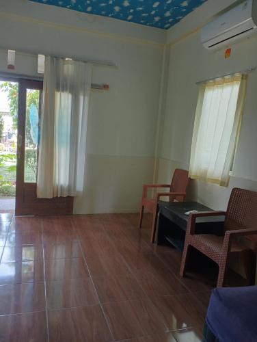 a living room with a table and chairs and a window at The Daun Puntik HomeStay in Pawenang
