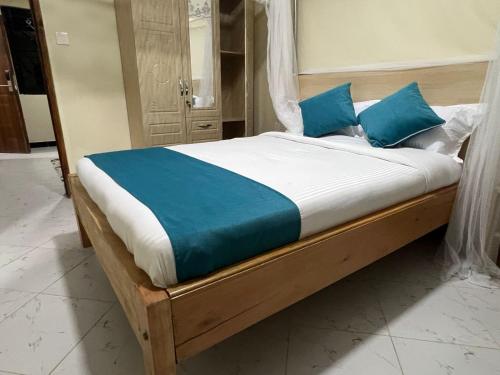 a bed with blue pillows on it in a room at Oltotoi Suites in Nairobi