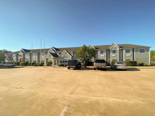 Un gran edificio con coches aparcados en un estacionamiento. en Motel 6 McAlester OK - South, en McAlester