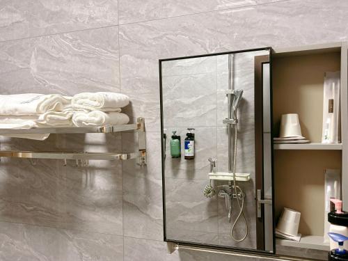 a shower with a glass door in a bathroom at Bed& in Mangshi