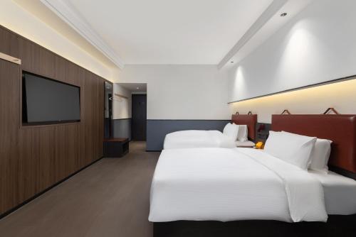 a hotel room with two beds and a flat screen tv at Mcsrh Hotel-Chengdu Jiuyanqiao in Chengdu