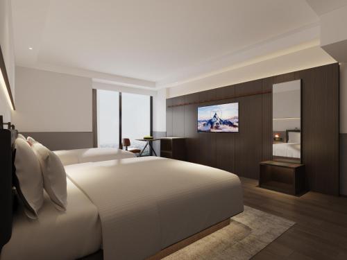 a hotel room with a bed and a television at Mcsrh Hotel-Chengdu Jiuyanqiao in Chengdu