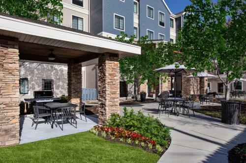 a patio with tables and chairs and an umbrella at Staybridge Suites Omaha 80th and Dodge by IHG in Omaha