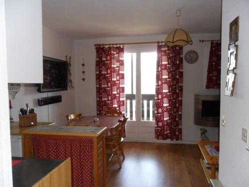une cuisine avec des rideaux rouges et une table avec des chaises dans l'établissement Studio Cabine Sud-Ouest avec Balcon et Parking à Barcelonnette - FR-1-804-9, à Barcelonnette