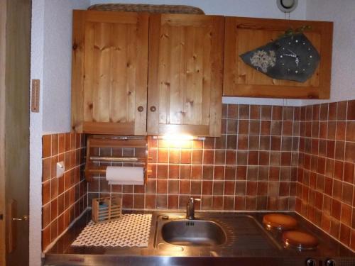 une cuisine avec un évier et des armoires en bois dans l'établissement Studio avec balcon à Barcelonnette, 4 couchages - FR-1-804-33, à Barcelonnette
