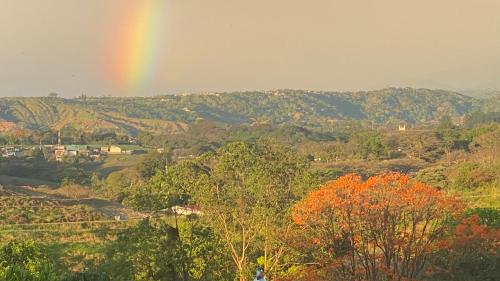 a rainbow in the sky over a field with trees at Casa Marigold in Coyol