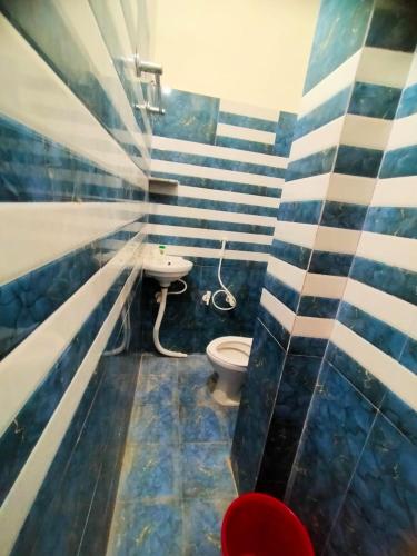 a bathroom with blue and white striped walls and a toilet at Shivay Guest house in Jasidih