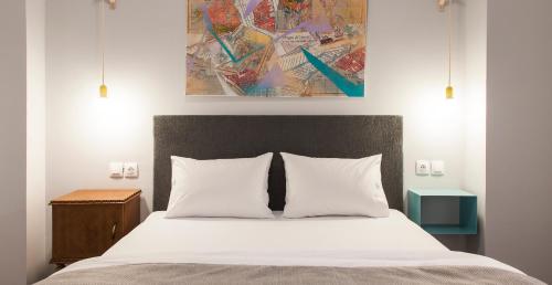 a bed with white pillows and a painting on the wall at The Caravan in Thessaloniki