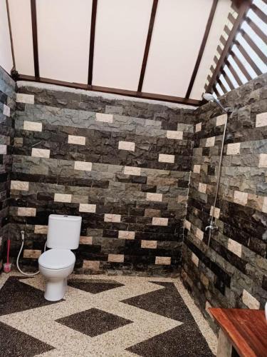a bathroom with a toilet in a brick wall at Turrall Bungalow in Puyung