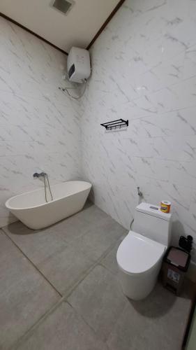a bathroom with a tub and a toilet and a sink at Villa D'Carik Bali in Denpasar