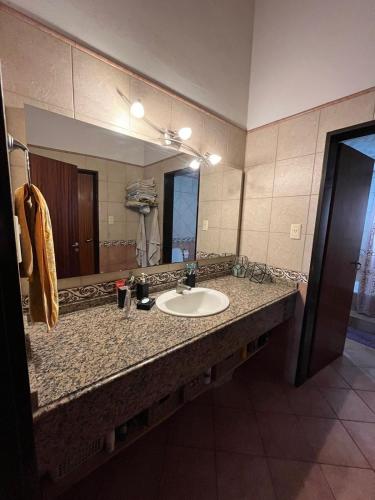 a bathroom with a sink and a large mirror at Spacious 3BDR house in Chivilcoy with swimming pool and view in Chivilcoy