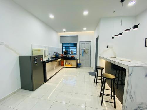a kitchen with a refrigerator and two bar stools at Alyn Home Muar II Wifi Netflix Coway in Muar