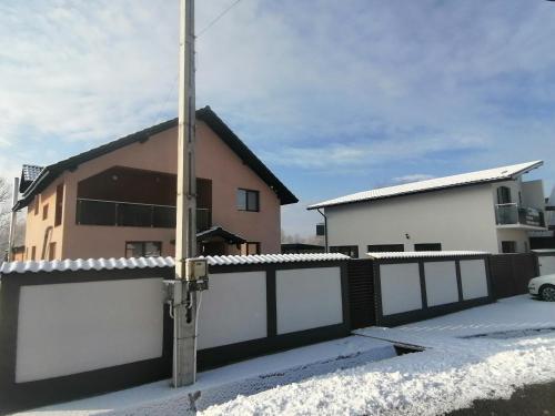 a house with a fence in the snow at Pensiunea Fira in Baia de Fier
