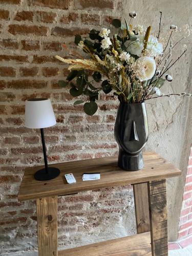 a vase of flowers on a table with a lamp at Les Hortensias in Canly
