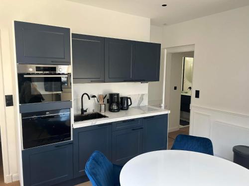 une cuisine avec des armoires bleues et une table blanche dans l'établissement Splendid appartement, à Rouen