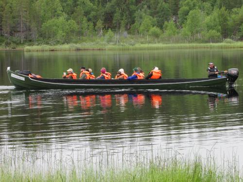 a group of people in a boat on a lake at Lemmenjoen Lumo - Nature Experience & Accommodation in Lemmenjoki