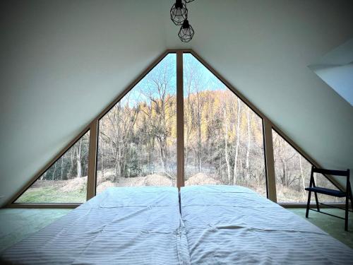 a bed in a room with a large window at Chata Šikulka in Osturňa