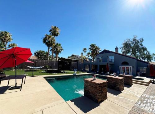 a swimming pool with a red umbrella and a house at Blue Waterfalls in Las Vegas