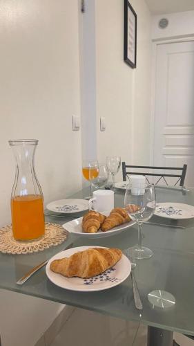 - une table avec des assiettes de pain et des verres de jus d'orange dans l'établissement Cosy entre Paris & Disney, à Bry-sur-Marne