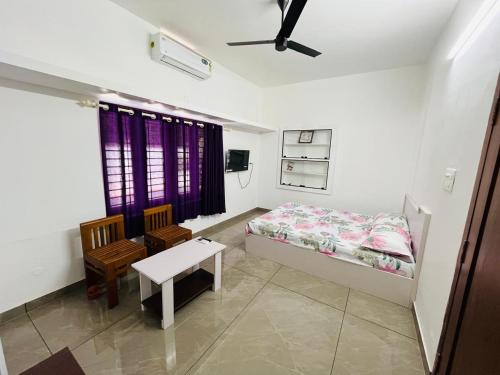 a bedroom with a bed and a table and a chair at Aagneyam mansion in Kozhikode