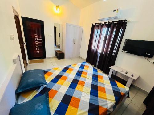 a bedroom with a colorful bed and a television at Aagneyam mansion in Kozhikode