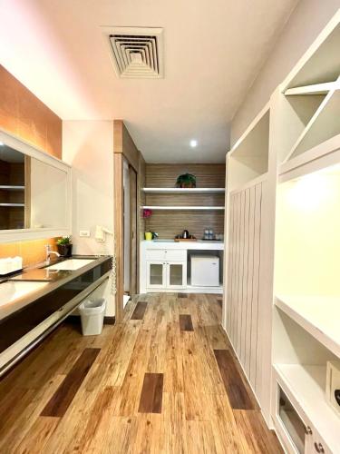 a large kitchen with wooden floors and white cabinets at 秘狗Nova Hotel in Pattaya South