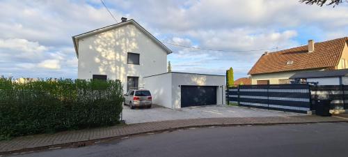 a white house with a car parked in a driveway at Orscholz apt with free parking & garden & bicycle storage in Orscholz
