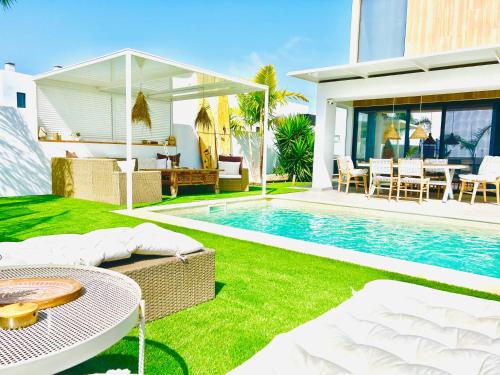 une cour arrière avec une piscine et une maison dans l'établissement El Palmeral - Exlusive Villa with Private, Heated Pool in Corralejo, à Corralejo