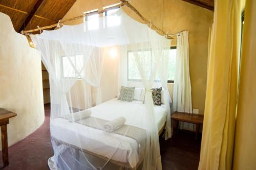 a bedroom with a bed with a canopy at Tree House Cottage, Garden Views, Hot Water in Praia do Tofo
