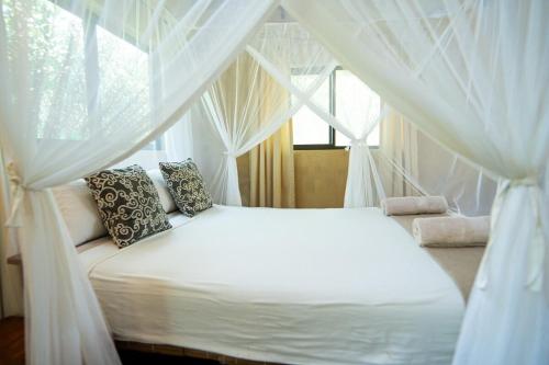 a bedroom with a white canopy bed with curtains at Tree House Cottage, Garden Views, Hot Water in Praia do Tofo