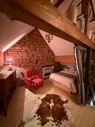 - une chambre mansardée avec un lit et un fauteuil rouge dans l'établissement Gîte Bien-être, Sauna, Bain nordique à Soucht (57), à Soucht