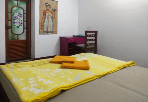 a bed with a yellow blanket on top of it at Marari Praise Beachfront Homestay in Mararikulam