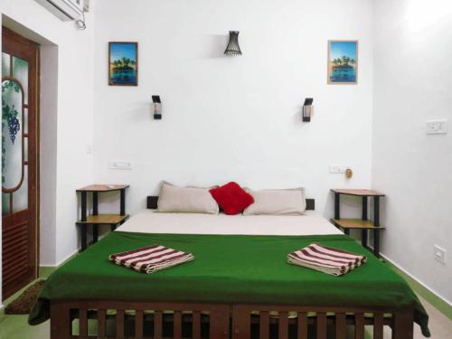 a bedroom with a bed with a green blanket at Marari Praise Beachfront Homestay in Mararikulam