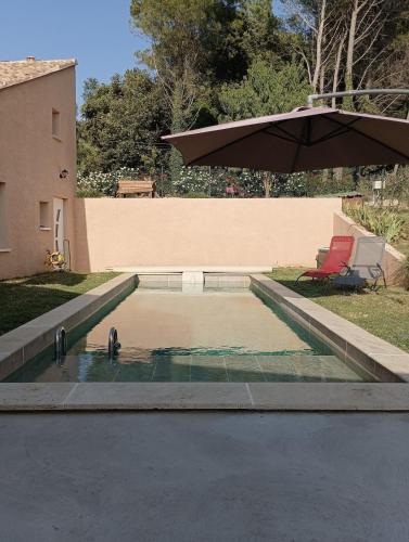 a pool of water with a chair and an umbrella at Maison de campagne avec piscine in Suze-la-Rousse