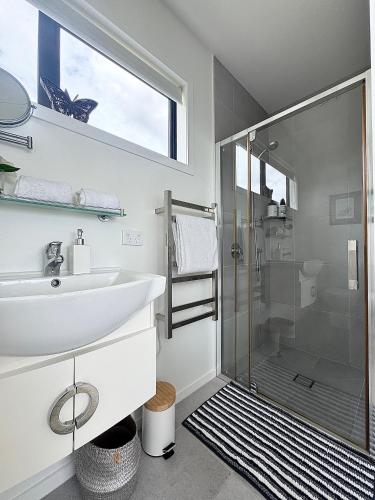 a bathroom with a glass shower and a sink at Raglan Travellers Rest Coastal Retreat in Raglan