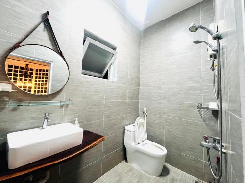 a bathroom with a sink and a toilet and a mirror at SIII Vũng Tàu Garden coffee & homestay in Vung Tau