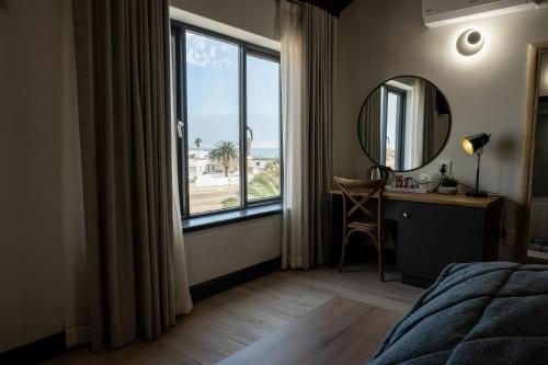 スワコプムントにあるGuesthouse Indongo Swakopmundのベッドルーム1室(大きな窓、鏡付きデスク付)