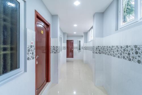 a hallway with white walls and a red door at Sam Residency in Puducherry