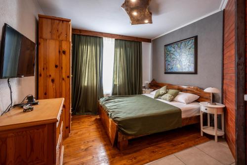 ein Schlafzimmer mit einem Bett, einem Schreibtisch und einem Fernseher in der Unterkunft Къща за гости Приказка in Klisura