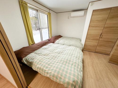 a small bedroom with a bed and a window at M&TTT in the nature in Shiraoi