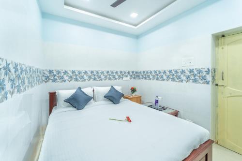 a bedroom with a white bed with blue pillows at Sam Residency in Puducherry