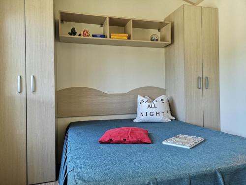 - une chambre avec un lit avec un oreiller rouge et un livre dans l'établissement Feriendorf Le Tamerici Mobilehome Pirri für 5 Personen, à Marina di Cecina