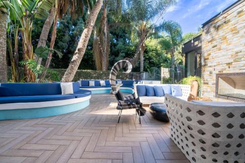 a patio with blue and white furniture and palm trees at Hotel La Jolla, Curio Collection by Hilton in San Diego